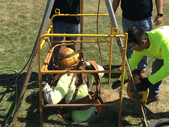 worker being lowered into manhole