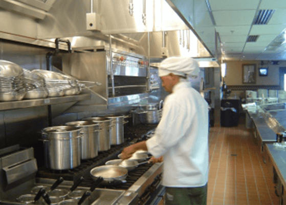 Chef standing at a stove working on cooking in a kitchen