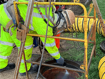 Worker spraying into a manhole