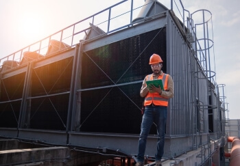 Worker checking notes by a cooling tower