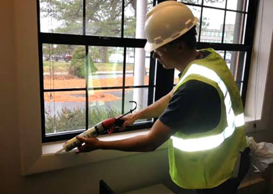 worker caulking a gap near a window