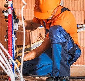 Worker retrofitting plumbing equipment