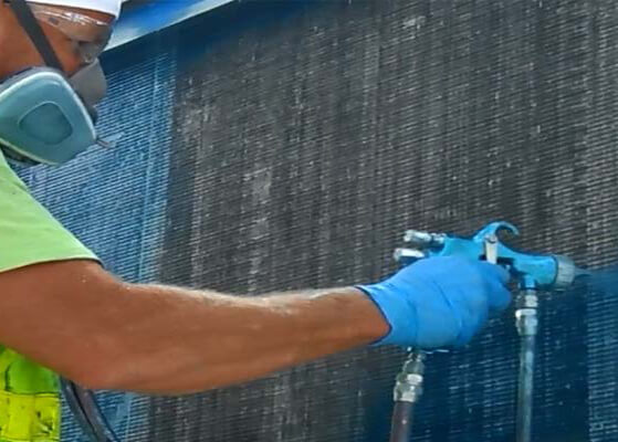 a worker coating the coils on an outdoor air handler