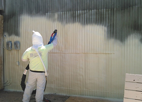 Worker applying spray foam to a base barracks